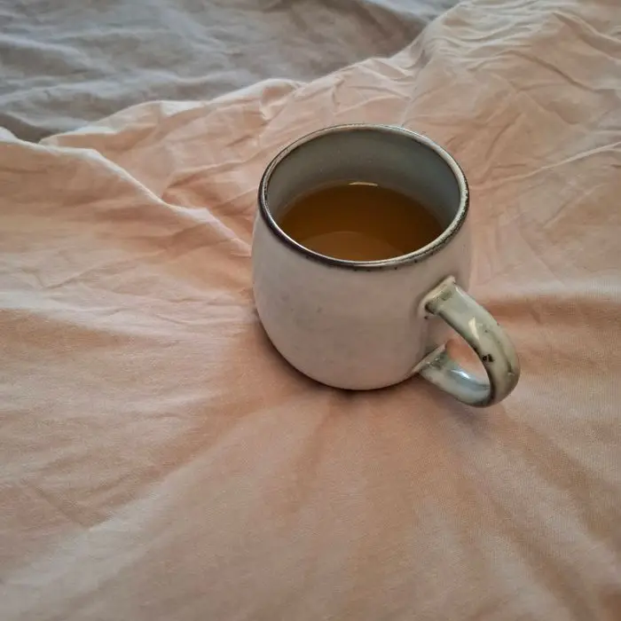A speckled stoneware mug of tea resting on soft linen